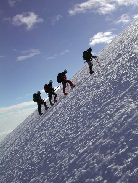 Fotografía de grupo ascendiendo por una montaña con hielo y nieve